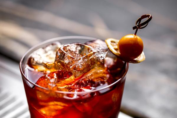 close up of a cocktail glass with ice cubes garnished with dried lemon and fruit