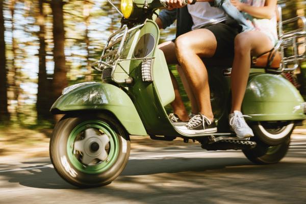 Bearded man on scooter with girlfriend outdoors.